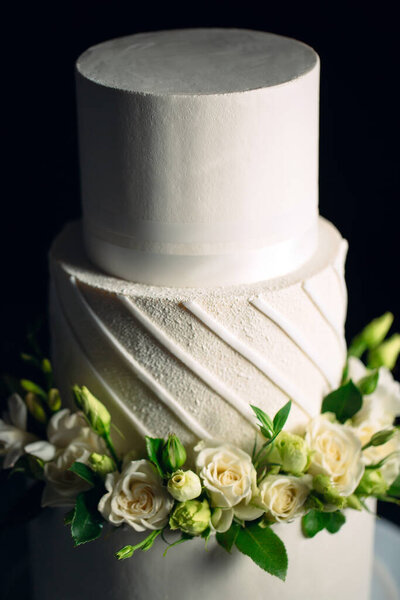 Cake is decorated with flowers on a dark background.