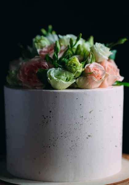 Bolo é decorado com flores em um fundo escuro. — Fotografia de Stock