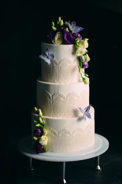 Tortul este decorat cu flori pe un fundal întunecat . — Fotografie, imagine de stoc