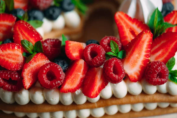 Pastel de frutas. Pastel decorado con bayas en un soporte de madera sobre un fondo negro. — Foto de Stock