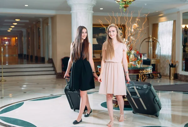 Young girls near reception desk in hotel. Young girls comes to the hotel. — Stock Photo, Image