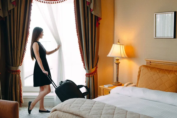 Wanita muda dengan koper tinggal di kamar hotel. — Stok Foto