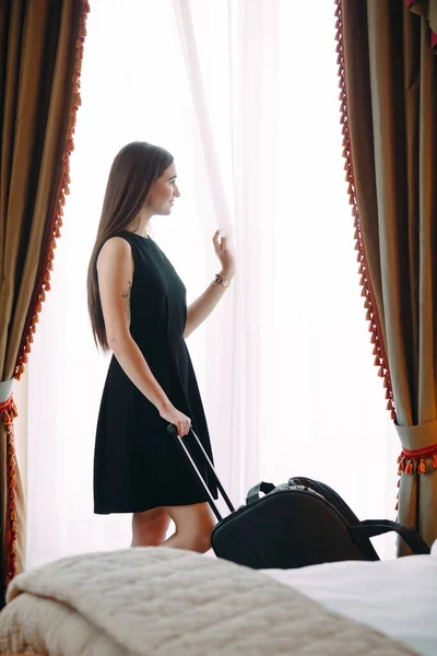 Wanita muda dengan koper tinggal di kamar hotel. — Stok Foto
