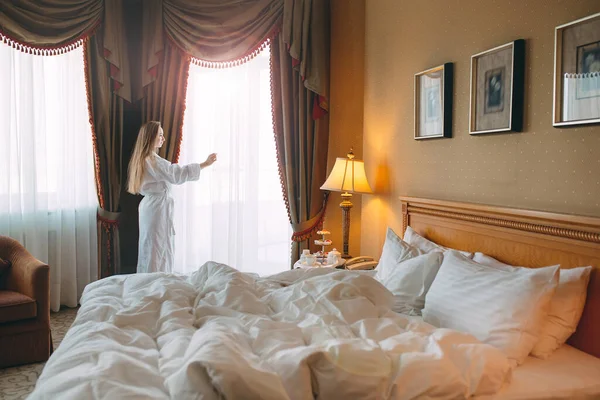 Woman in bathrobe stay near the window in hotel room. — Stock Photo, Image