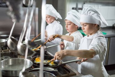 Çocuklar restoranın mutfağında yumurta pişiriyor..