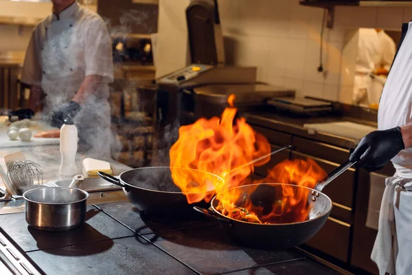 Moderne Küche. Köche bereiten die Mahlzeiten auf dem Herd in der Küche des Restaurants oder Hotels zu. Das Feuer in der Küche. — Stockfoto