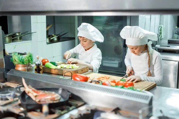 Children grind vegetables in the kitchen of a restaurant. — Stock Photo, Image