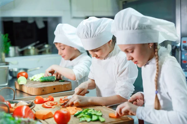 Children grind vegetables in the kitchen of a restaurant. — Stock Photo, Image