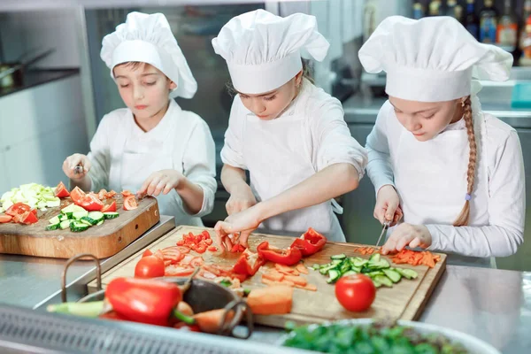 Los niños muelen verduras en la cocina de un restaurante. — Foto de Stock