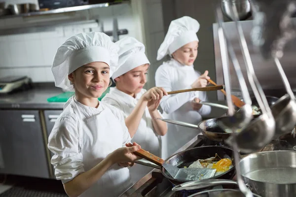 Children cook eggs in the kitchen at the Restaurant.