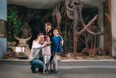 Bir aile paleontoloji müzesinde mamut iskeletine karşı selfie çekiyor..