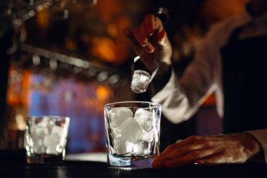 Barmen bardaklara buz doldurur..