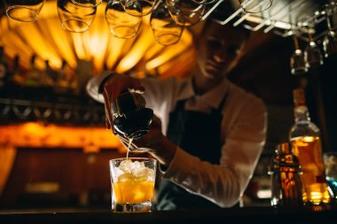 Barmen kokteyle narenciye sıkıyor..