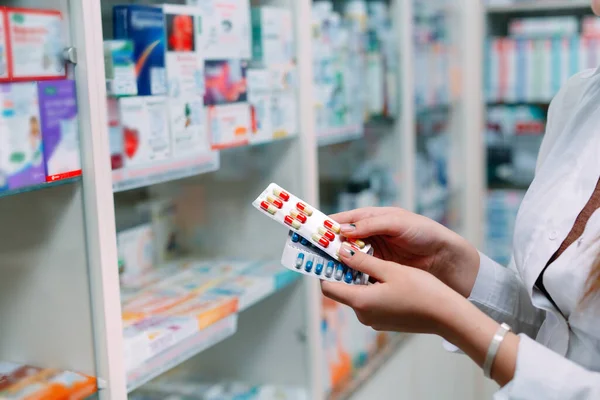 Farmacéutico que contiene la caja de medicamentos y los envases de cápsulas en farmacia. — Foto de Stock