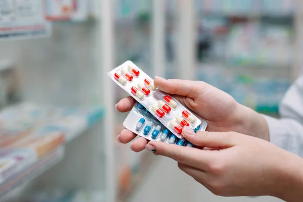 Farmacéutico que contiene la caja de medicamentos y los envases de cápsulas en farmacia. — Foto de Stock