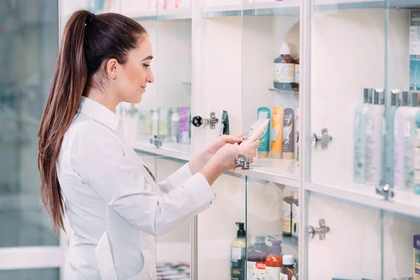 Linda mujer farmacéutica que ofrece productos de cuidado corporal en la farmacia. — Foto de Stock