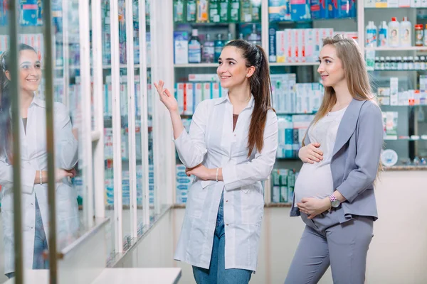 Una hermosa mujer embarazada consulta en una farmacia. — Foto de Stock