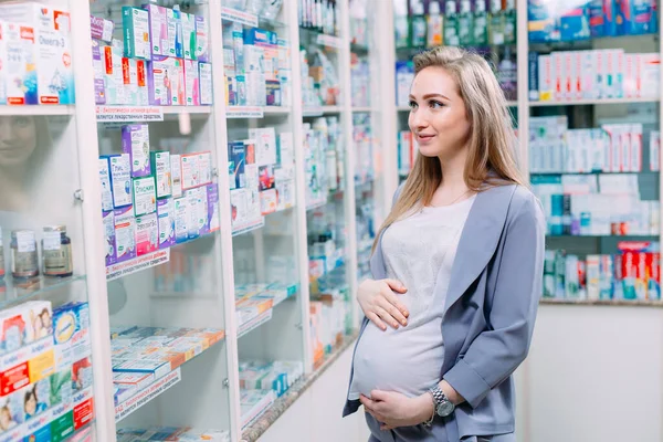 Una hermosa mujer embarazada consulta en una farmacia. — Foto de Stock