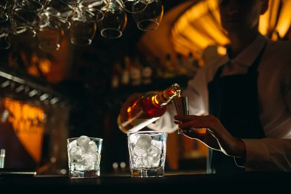 Der Barkeeper gießt Whisky auf die Theke. — Stockfoto