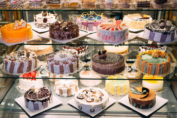 Pastry shop glass display with selection of cream or fruit cake.
