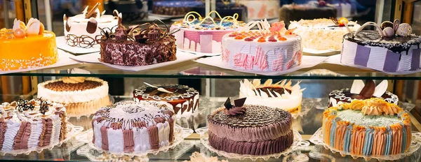 Gebak glazen display met selectie van room of fruit cake. — Stockfoto