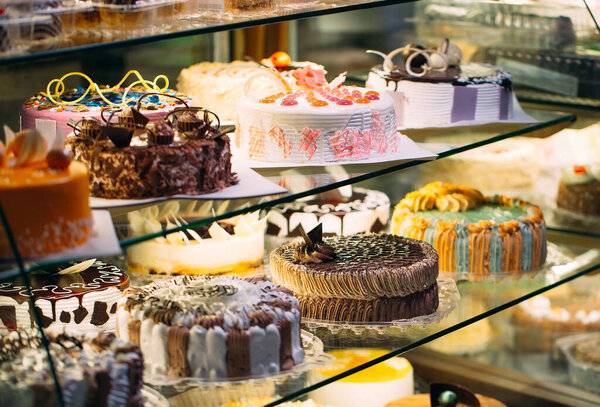 Pastry shop glass display with selection of cream or fruit cake.