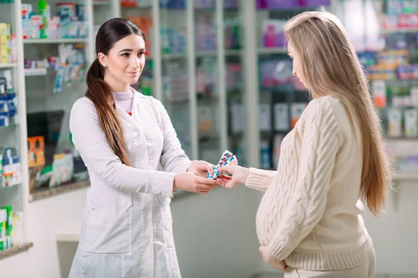 Una hermosa mujer embarazada consulta en una farmacia. — Foto de Stock