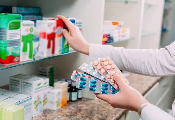 Farmacéutico que contiene la caja de medicamentos y los envases de cápsulas en farmacia. — Foto de Stock
