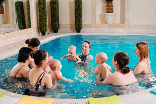 Grupa matek z małymi dziećmi na zajęciach pływania z trenerem. — Zdjęcie stockowe