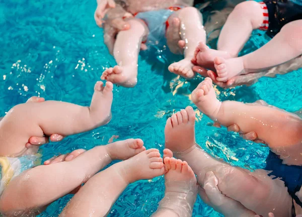 Een groep moeders met hun jonge kinderen in een zwemklas met een coach. — Stockfoto