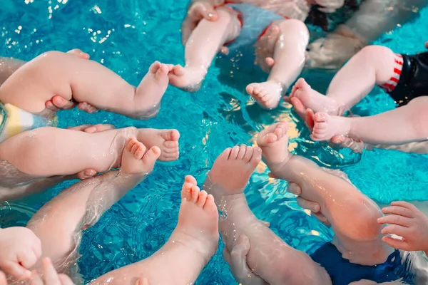 Een groep moeders met hun jonge kinderen in een zwemklas met een coach. — Stockfoto