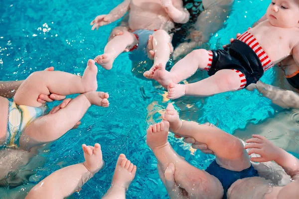 Un groupe de mères avec leurs jeunes enfants dans une classe de natation pour enfants avec un entraîneur. — Photo