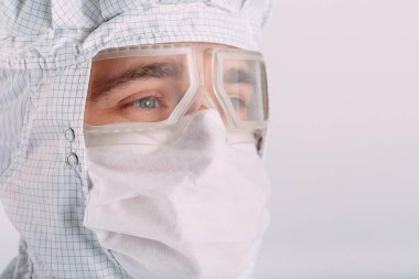 Tıbbi maske, koruyucu gözlük ve kimyasal elbise takmış Avrupalı bir erkek doktorun portresi..