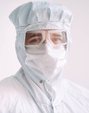 Tıbbi maske, koruyucu gözlük ve kimyasal elbise takmış Avrupalı bir erkek doktorun portresi..