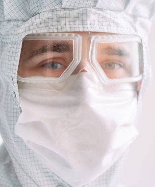 Tıbbi maske, koruyucu gözlük ve kimyasal elbise takmış Avrupalı bir erkek doktorun portresi..