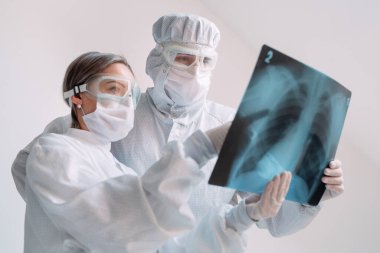 Beyaz arka planda duran doktorlar klinikteki Covid-19 hastasının zatürresi için röntgen çekiyorlar. Coronavirus konsepti.