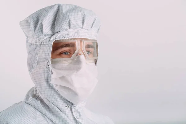 Eurooppalaisen ulkonäöltään eurooppalaisen miehen muotokuva lääketieteellisessä naamiossa, suojalaseissa ja kemiallisessa puvussa. — kuvapankkivalokuva