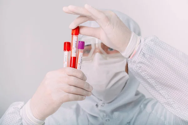 doctor man in flu mask and protective gloves holding a test tube with a coronavirus blood sample. Prevent flu disease Coronavirus.