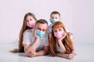 Karantina sırasında maskeli genç bir aile.
