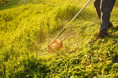 Çim biçme makinesi. Gün batımında çimenleri biçen işçi..