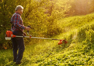 Çim biçme makinesi. Gün batımında çimenleri biçen işçi..