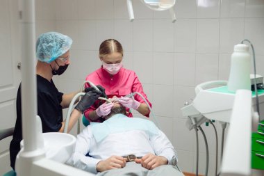 Profesyonel diş temizliği. Dişçi, erkek bir hastanın dişlerini temizler..