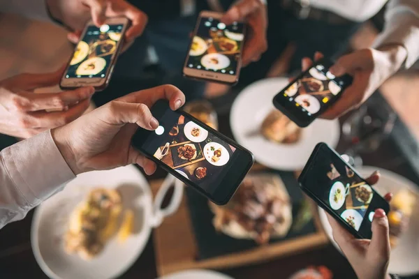 Grupa przyjaciół wychodzi i robi zdjęcie jedzenia razem z telefonem komórkowym — Zdjęcie stockowe