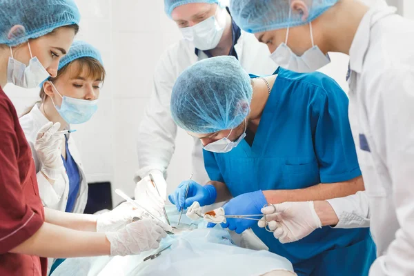 Cerrahi tiyatroda çalışan bir grup cerrah. Sağlık ekibi çelik tıbbi aletler taşıyan koruyucu maskeler takıyor.