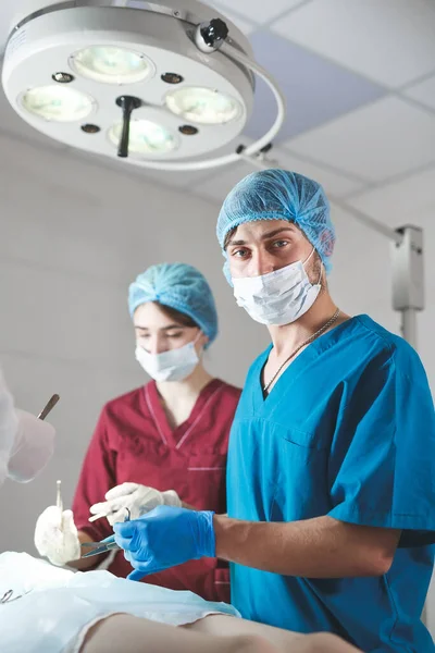 Portrait de chirurgiens au travail, opérant en uniforme, regardant la caméra. — Photo