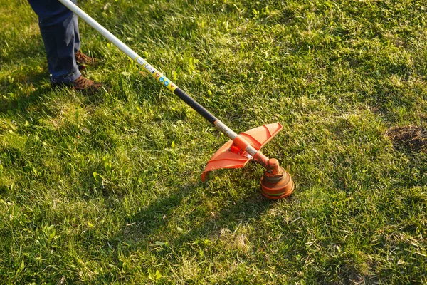 Podadora - trabajador de corte de césped en el patio verde al atardecer. — Foto de Stock