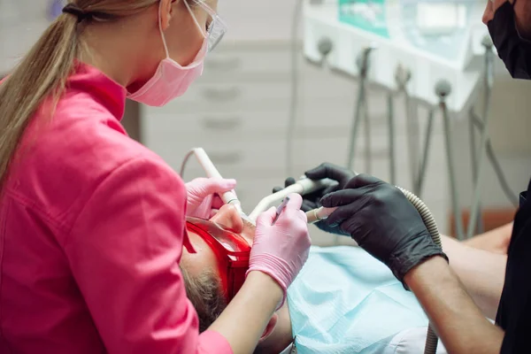 Professional teeth cleaning. Dentist cleans the teeth of a male patient.