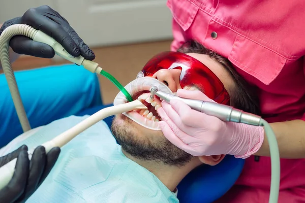 Professional teeth cleaning. Dentist cleans the teeth of a male patient.