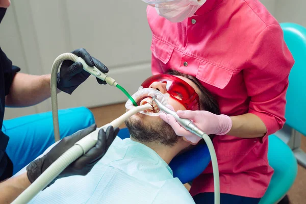 Professionell tandrengöring. Tandläkare rengör tänderna på en manlig patient. — Stockfoto