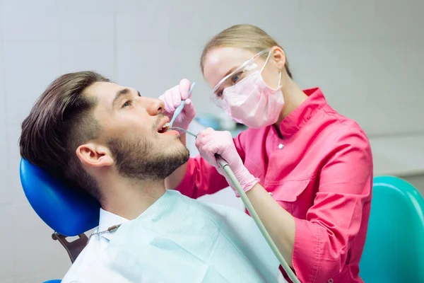 Profesjonalne czyszczenie zębów. Dentysta myje zęby męskiemu pacjentowi. — Zdjęcie stockowe